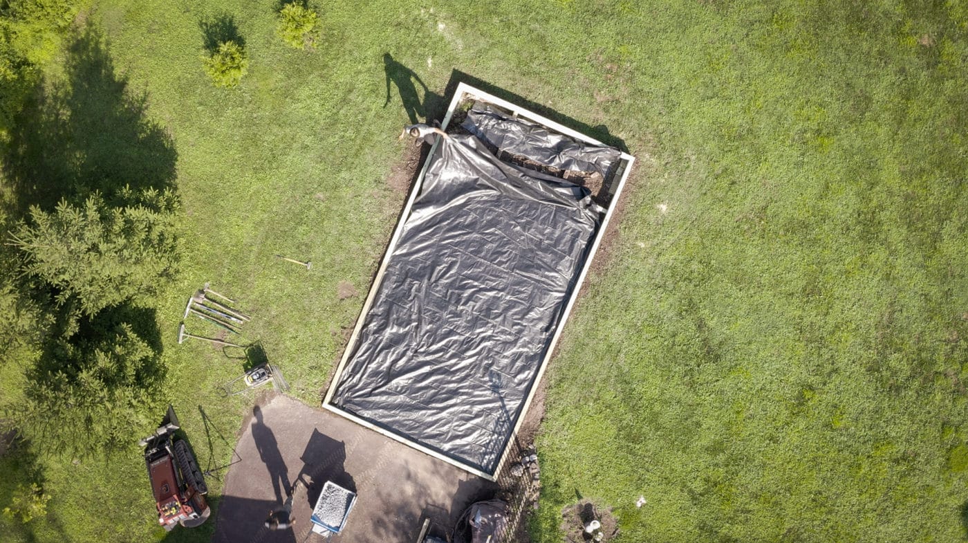 A shed site prep contractor in PA adding weed barrier fabric to a shed foundation