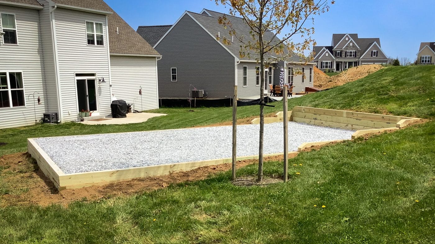 A gravel fire pit area on a slope behind a house