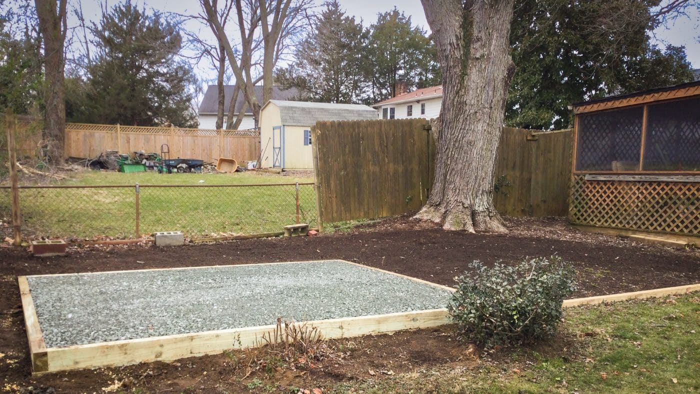 A gravel fire pit patio area in a backyard