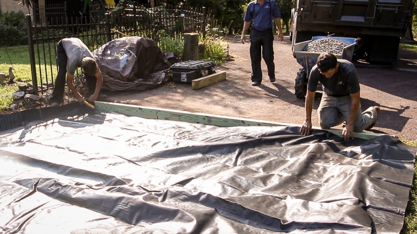 Installing stabilization fabric weed barrier for a gravel patio fire pit area