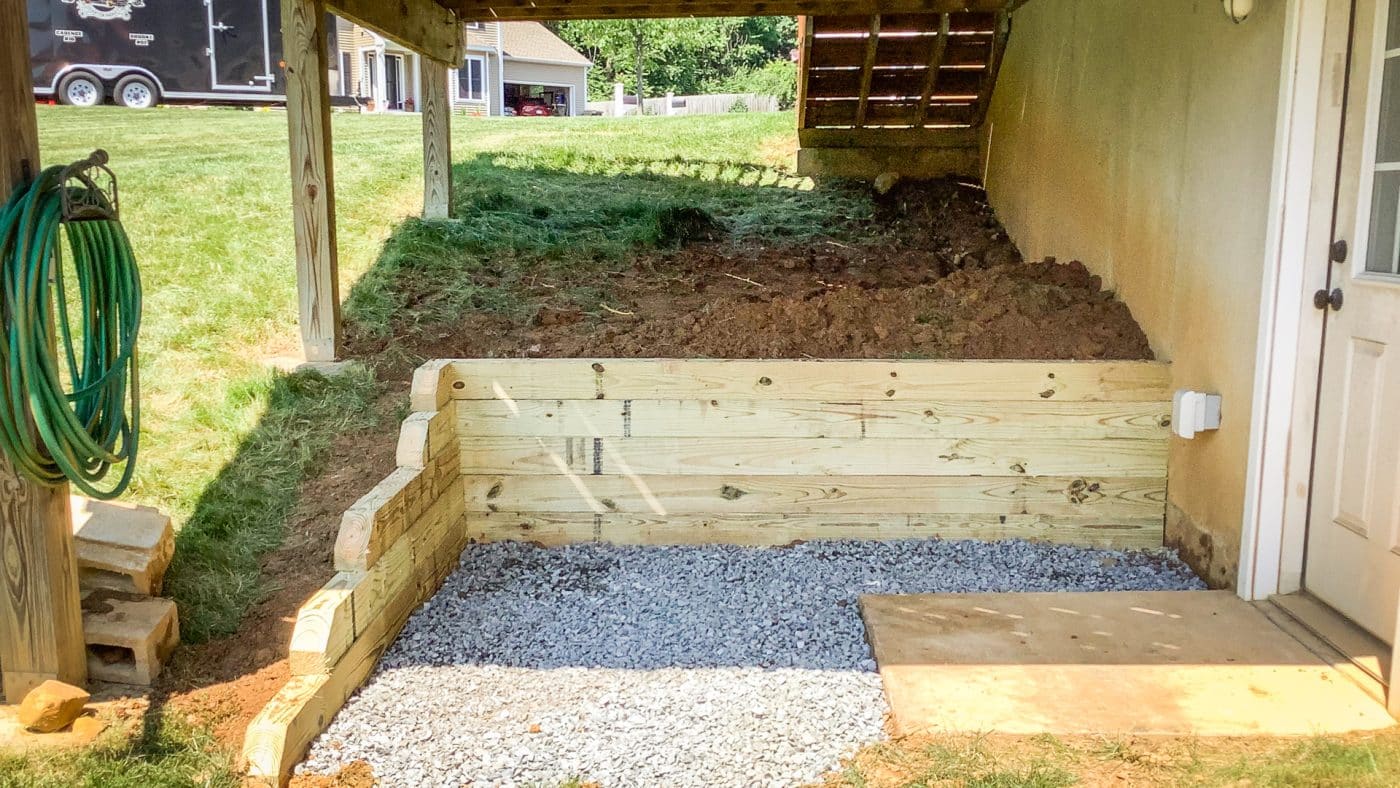 A basement entrance with gravel under a deck