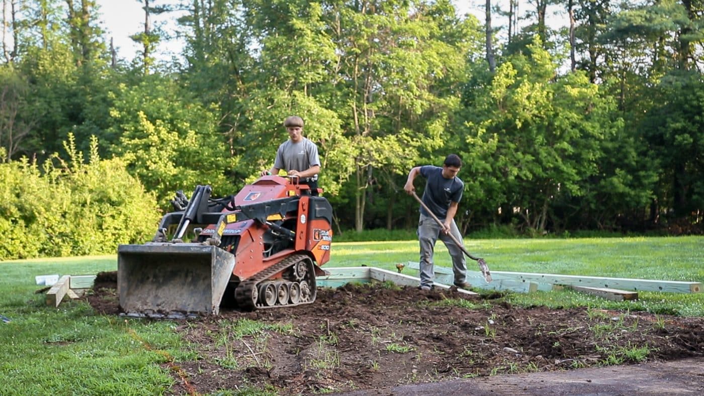 men excavating the ground as one of the first steps on how to build a shed base on uneven ground