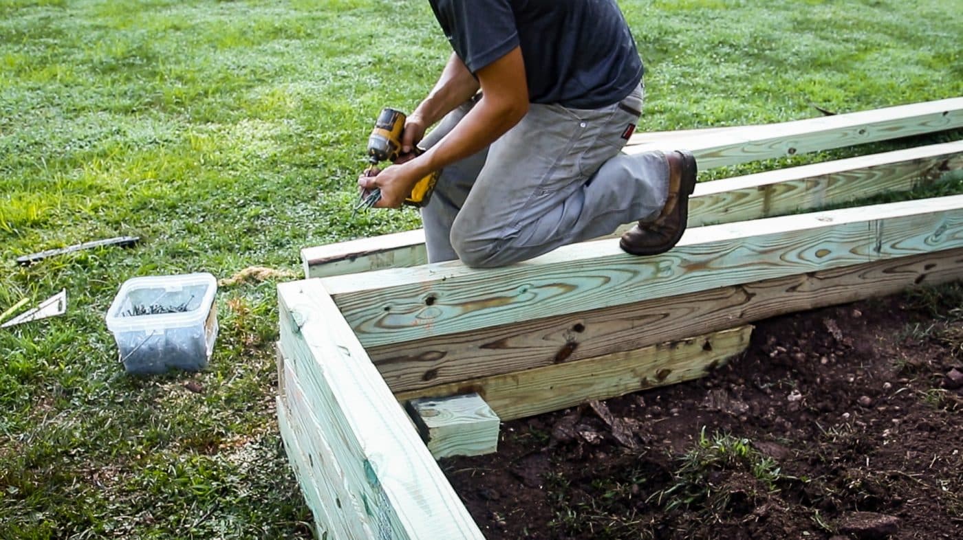 man working on shed perimeter as a step on how to build a shed base on uneven ground