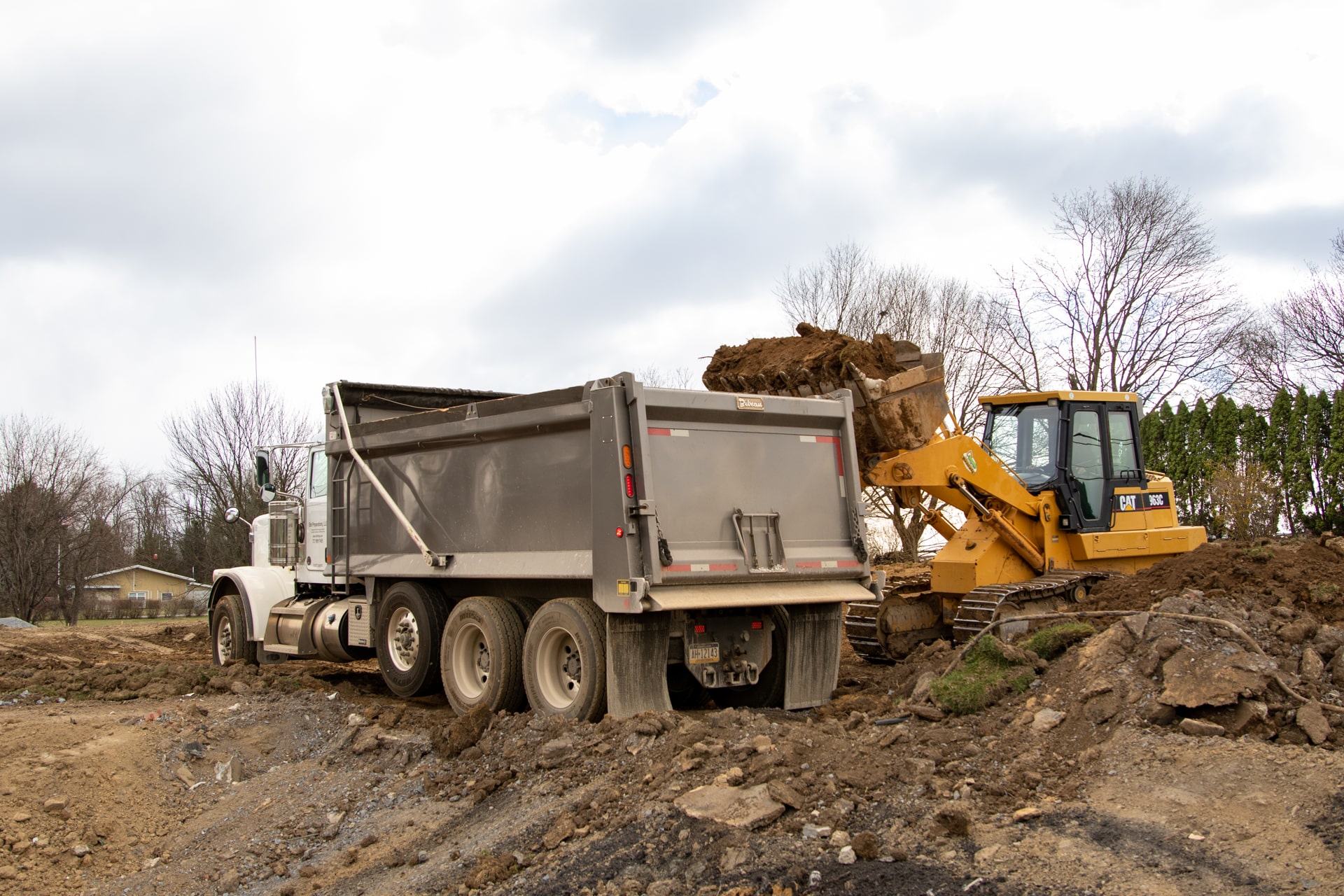 dump truck by cat skid during commercial excavation